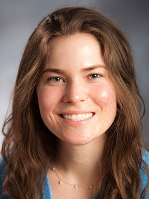 White woman with brown hair and blues eyes wearing a blue sweater